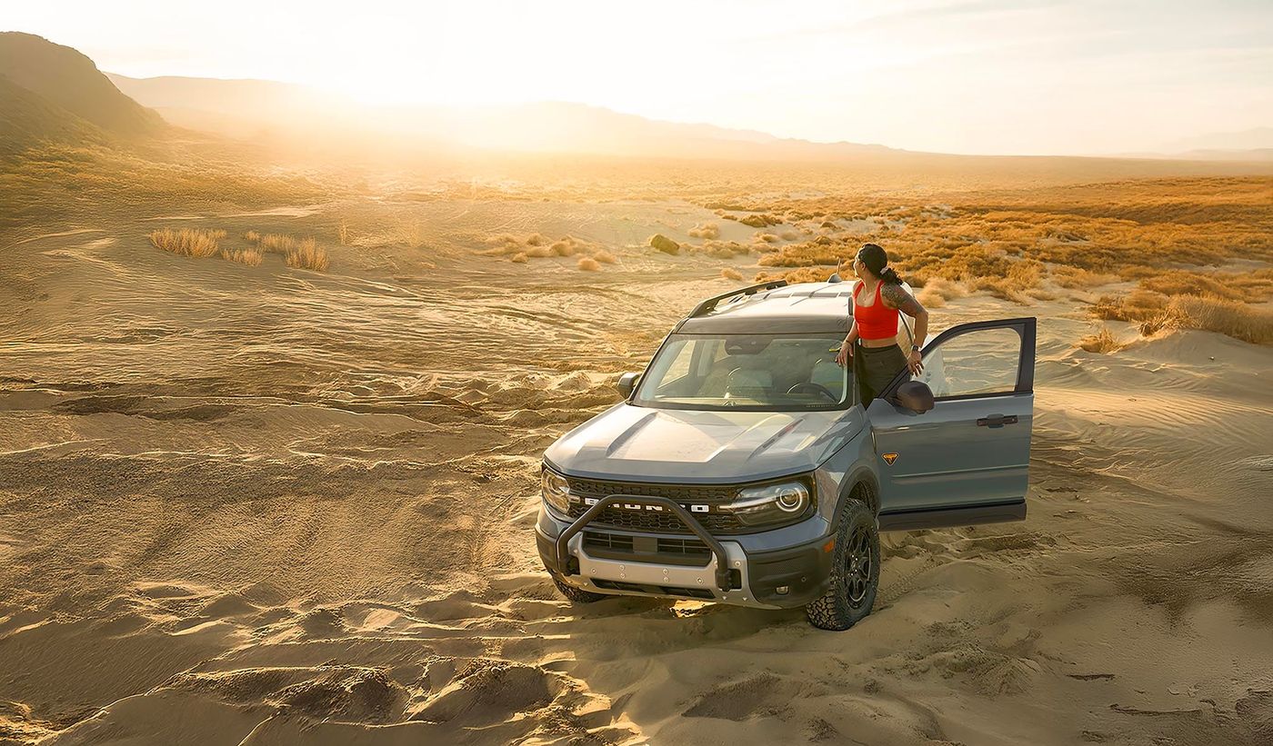 Ford Bronco Sport parked in the desert with a person standing beside it