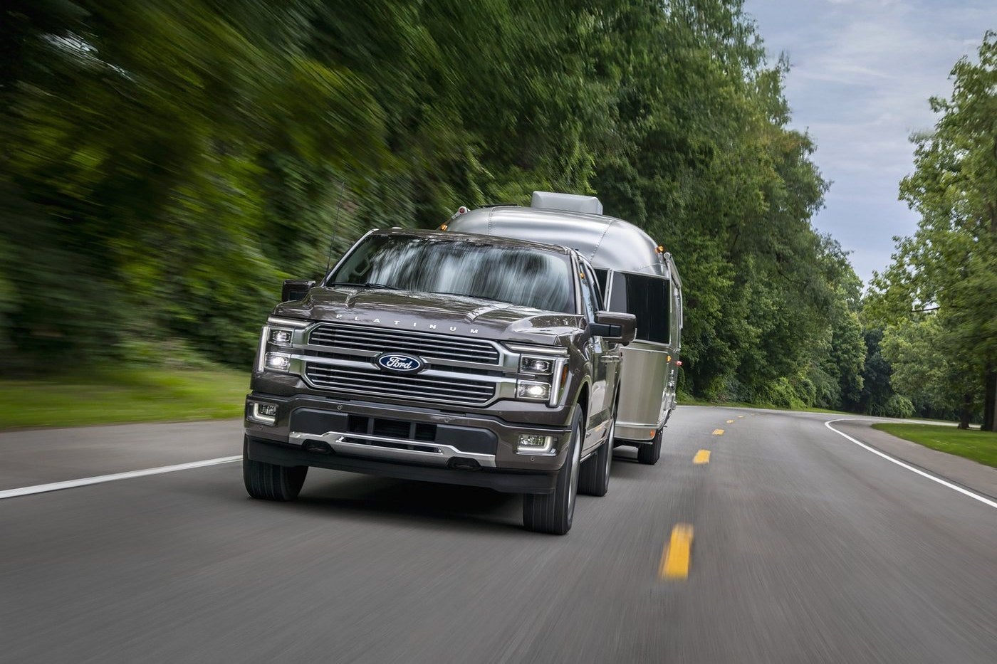 Ford F-150 Platinum in Marsh Gray pulling a camper, a truck option for Gordon, TX families who tow