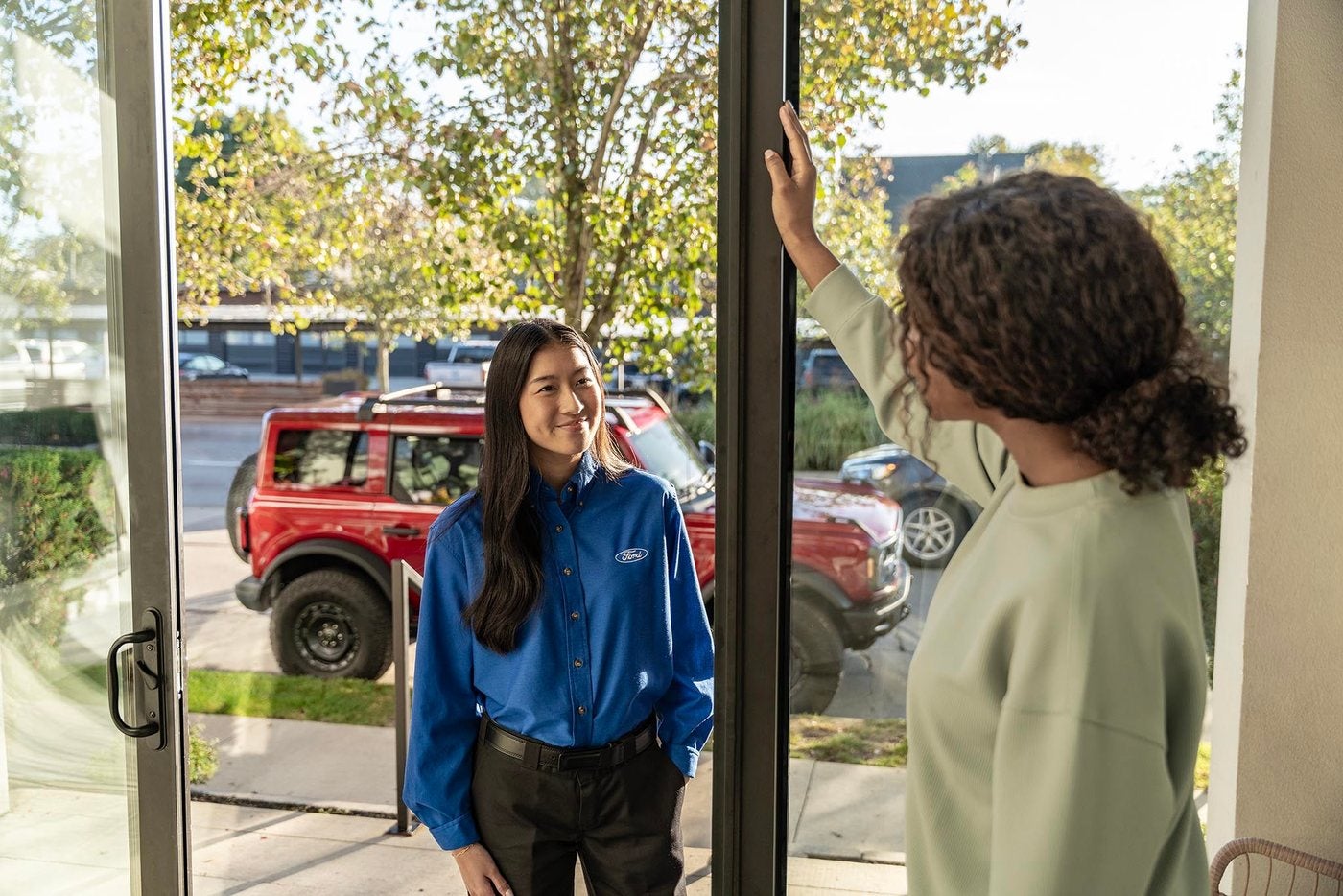 Ford representative greeting an owner beside a Ford vehicle in a driveway
